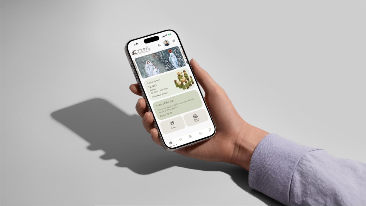A hand holding a phone with the St John's app home screen open